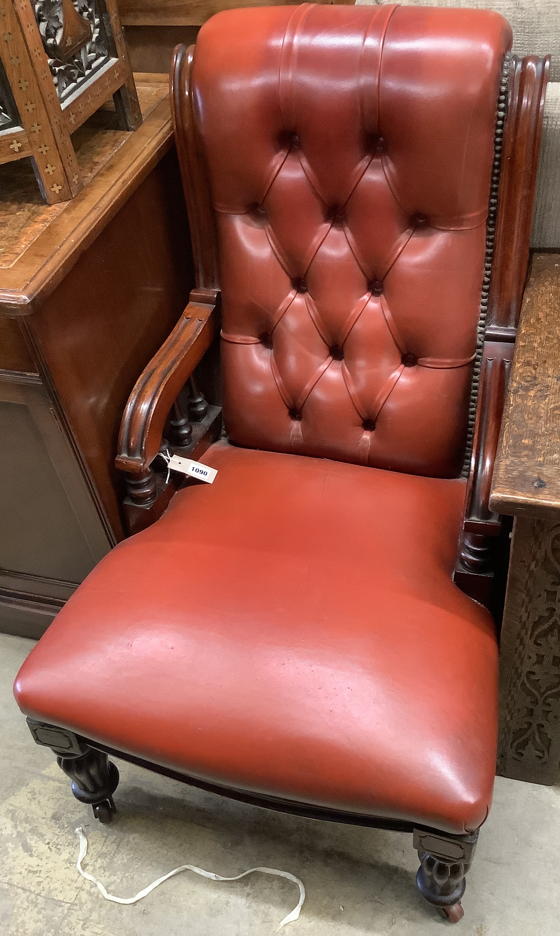 A Victorian mahogany easy chair, upholstered in buttoned red hide